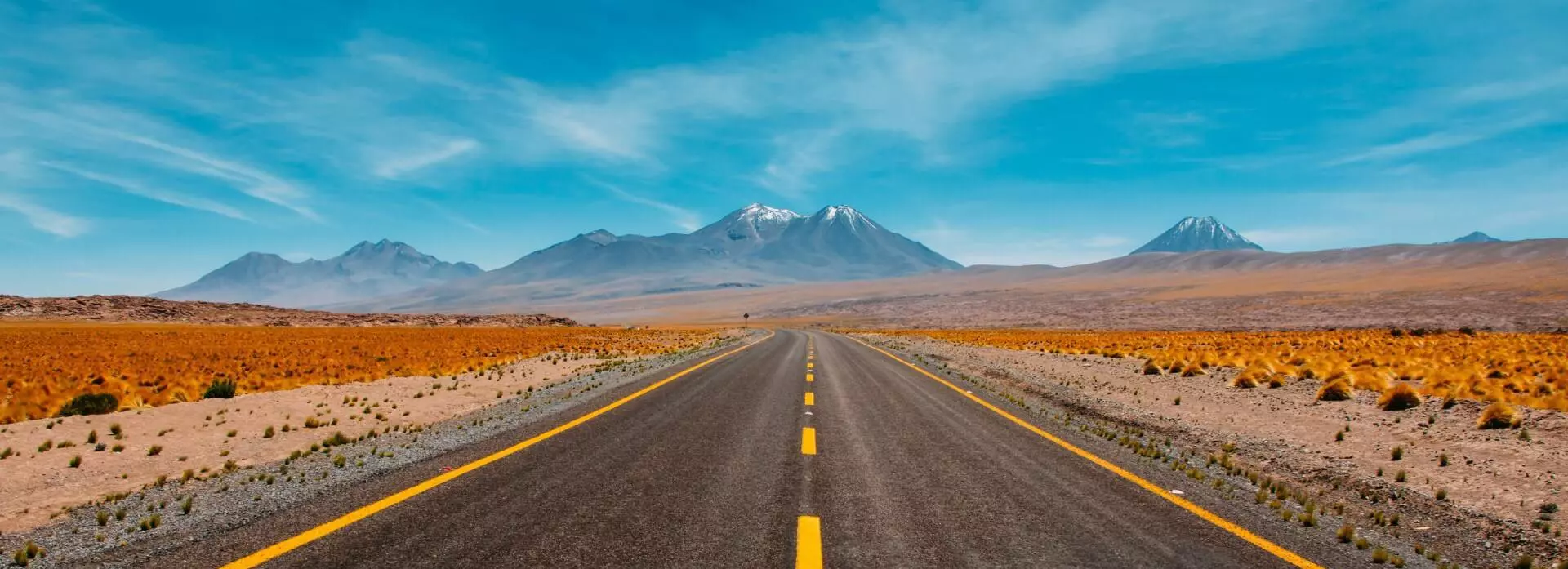 Eine Straße in der Atacama Wüste in Chile mit Bergen im Hintergrund